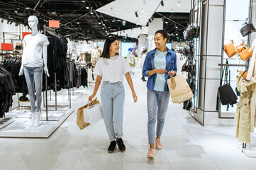 Canvas Print - Girlfriends with bags walks in clothing store