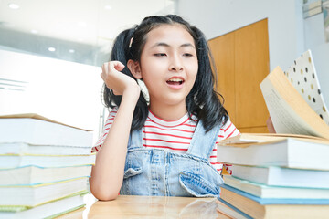Preteen Vietnamese girl looking at many books on her desk
