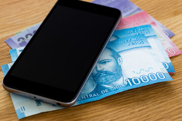 Chile currency, pesos, banknotes lying together with a mobile phone on a table