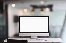 Workspace Computer Monitor With A White Blank Screen On White Table.