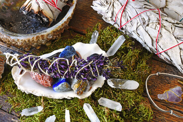 Wall Mural - A close up image of a clear quartz crystal grid on moss with white sage smudge sticks and a home made pendulum. 