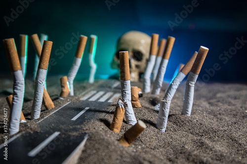 Photographie Ashtray and butts cigarettes on dark background. Selective focus
