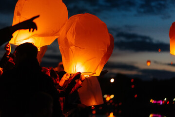 The child starts the lanterns into the sky on a dark night. Celebration, traditions of the new year.