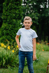 A cute boy stands in the Park and smiles.