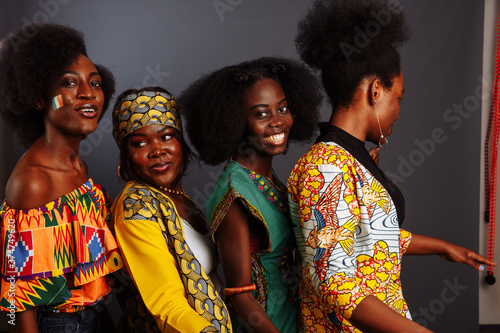 Plakat Four young beautiful African fashion models have fun and laughing in traditional dress. Women from the Congo Republic, Ivory Coast, and Zimbabwe