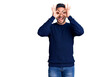 © Krakenimages.com - Young handsome man wearing casual clothes doing ok gesture like binoculars sticking tongue out, eyes looking through fingers. crazy expression.