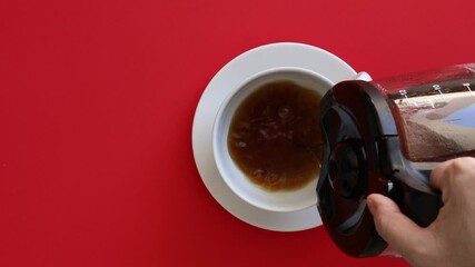 Wall Mural - Pouring a Cup of Coffee on a Red Background 