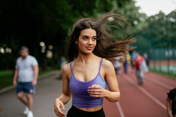 Happy athletic woman running in nature in the morning. Young woman training outdoors....