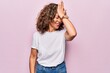 Middle age beautiful woman wearing casual t-shirt standing over isolated pink background surprised with hand on head for mistake, remember error. Forgot, bad memory concept.
