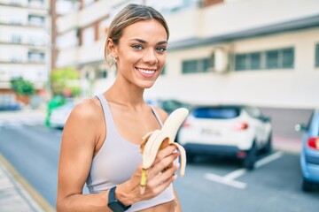 Young cauciasian fitness woman wearing sport clothes training outdoors eating healthy banana for strength and energy