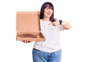 Young plus size woman holding delivery pizza box smiling happy pointing with hand and finger