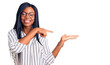 © Krakenimages.com - Young african american woman wearing casual clothes and glasses amazed and smiling to the camera while presenting with hand and pointing with finger.