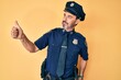 © Krakenimages.com - Middle age hispanic man wearing police uniform looking proud, smiling doing thumbs up gesture to the side