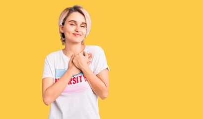 Young beautiful blonde woman wearing t shirt with diversity word message smiling with hands on chest with closed eyes and grateful gesture on face. health concept.