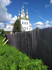 Beautiful old white church behind wooden fence at summer day