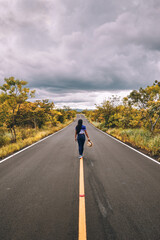 Female traveler holding a hat walking in the center of a quiet road at masaya volcano national park