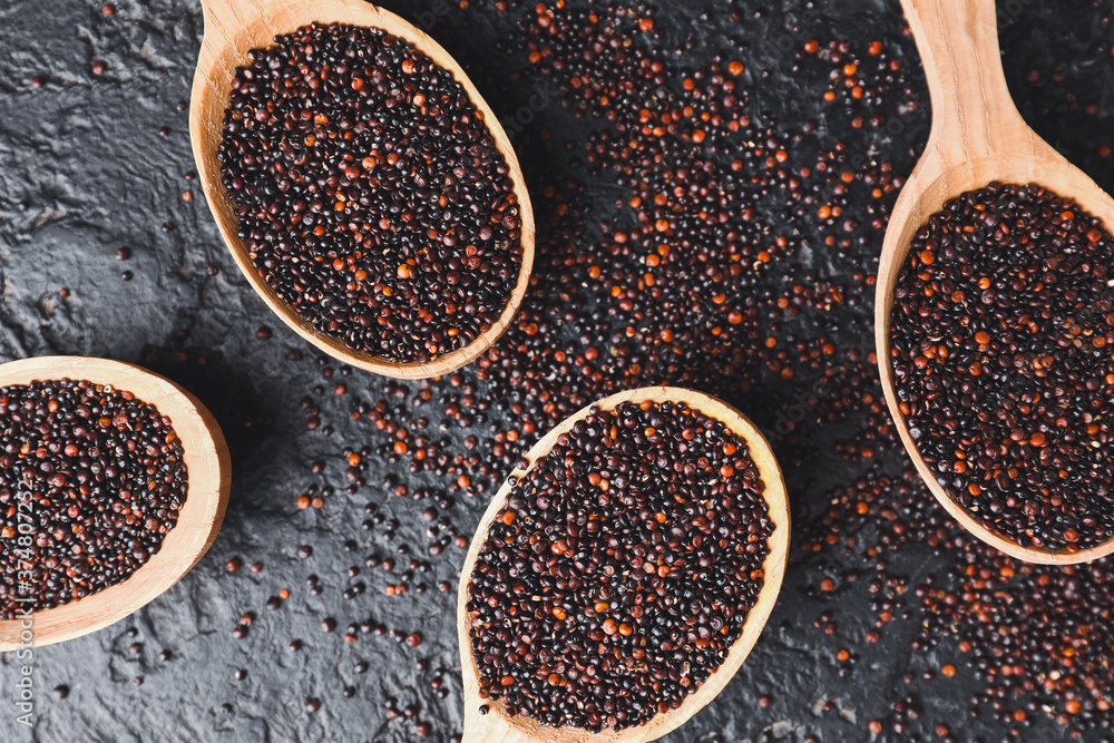 Spoons with healthy quinoa on dark background