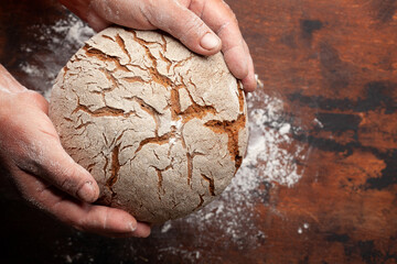 Baker holding fresh baked homemade bread