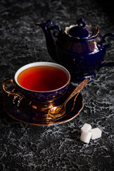 Vintage tea cup with teapot on a dark background