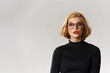 © SHOTPRIME STUDIO - Blonde girl with glasses red lips black blouse cropped view glamor light background studio