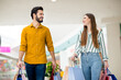 © deagreez - Portrait of cheerful friends spouses man woman have free time in shopping mall go walk hold many packages purchase wear yellow striped shirt denim jeans