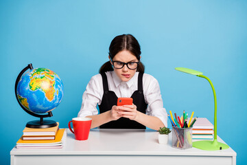 Canvas Print - Frustrated girl college student sit table have geography globe lesson break mug beverage use smartphone lose race game wear white blouse black overall uniform isolated blue color background