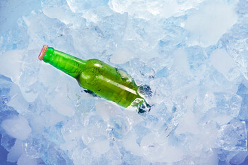 Wall Mural - Green bottle of fresh beer in stack of ice cubes