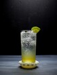 Ginger whiskey highball cocktail in a collins glass garnished with lime isolated against a dark grey and black background