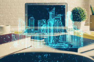 Desktop computer background in office and big town buildings hologram drawing. Double exposure. Smart city concept.