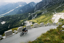 Professional Road Cyclist On Training Trip In Alps. Amazing Epic Landscape Of Mountain Road And Cyclist On Travel Tour Bike Descends Steep Hill. Inspiring Photo Of Cycling Sport