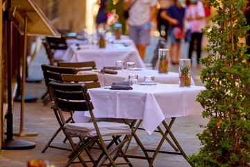 Summer vacation in Tuscany. Tables decorated on a white tablecloth on the street waiting for guests. Pienza, Italy