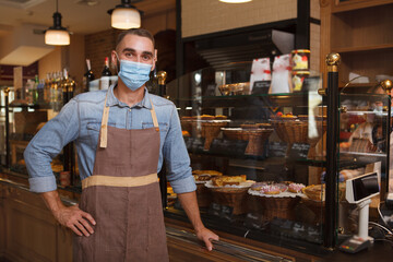 Male baker wearing medical face mask working at his bakery store during coronavirus quarantine