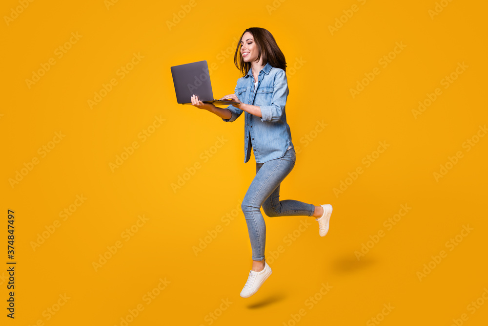 Full length body size profile side view of nice smart clever slim fit cheerful girl jumping walking using laptop watch video lesson tutorial isolated bright vivid shine vibrant yellow color background - obrazy, fototapety, plakaty 