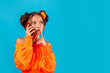 © Karine_k.a - stylish girl making a call with her mobile phone. isolated on blue background. looking doubtfully sideways. close up. copy space