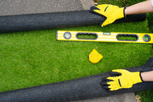 Artificial Grass Roll And Tools In Female Hands. View Above.