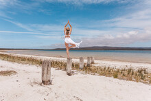Beautiful Woman Balance On Wooden Post Yoga Pose In Swimwear And Sarong