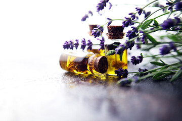 lavender oil in a glass bottle on a background of fresh flowers.