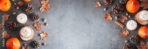 Fotografía Autumn border banner with natural pine cones, pumpkins, dried leaves and pumpkin latte on dark grey stone top, top view, copy space