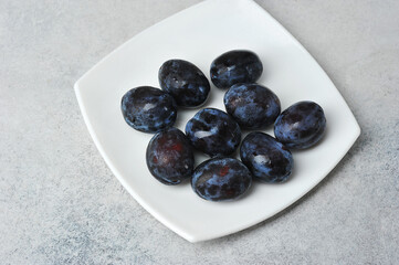 Wall Mural - juicy ripe black and blue plums on a plate