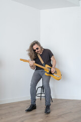 Sticker - Shallow focus shot of a middle-aged male playing the guitar in a white room