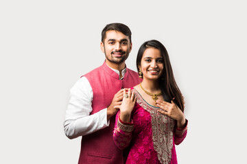 Wall Mural - Handsome young Indian man presenting expensive gold necklace to pretty young girl friend or wife