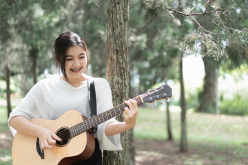 Wall Mural - cute girl playing guitar at the garden