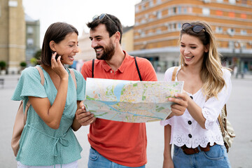 Wall Mural - happy traveling tourists sightseeing with map and having fun