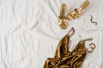 sexy fashion concept with women's clothes and accessories. golden shoes, brown silk dress, golden ne