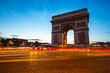 The night view of triumphal arch and traffic in Paris, France.