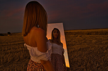 model looks at the sunset with her mirror