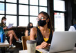 © Halfpoint - Portrait of young businesswoman with face mask working indoors in office.