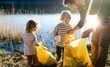 Father with small kids collecting rubbish outdoors in nature, plogging concept.