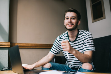 Delighted male surfing laptop on sofa