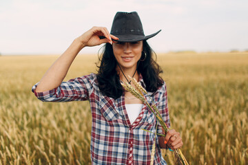 Woman american farmer wearing cowboy hat, plaid shirt and jeans at wheat field